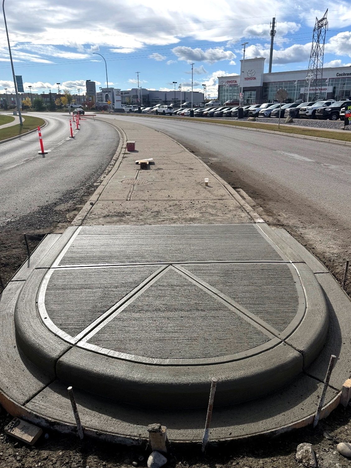 Finished broom-finished concrete roundabout medallion and traffic island with patterned control joints at the Cochrane Toyota dealership, installed by SiteWorx Concrete