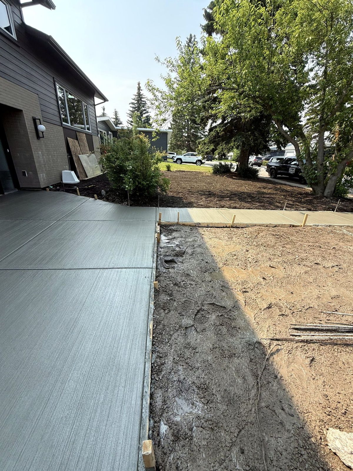 Broom-finished residential concrete driveway and walkway with clean control joints alongside a modern Calgary home with gravel base prep, poured by SiteWorx Concrete
