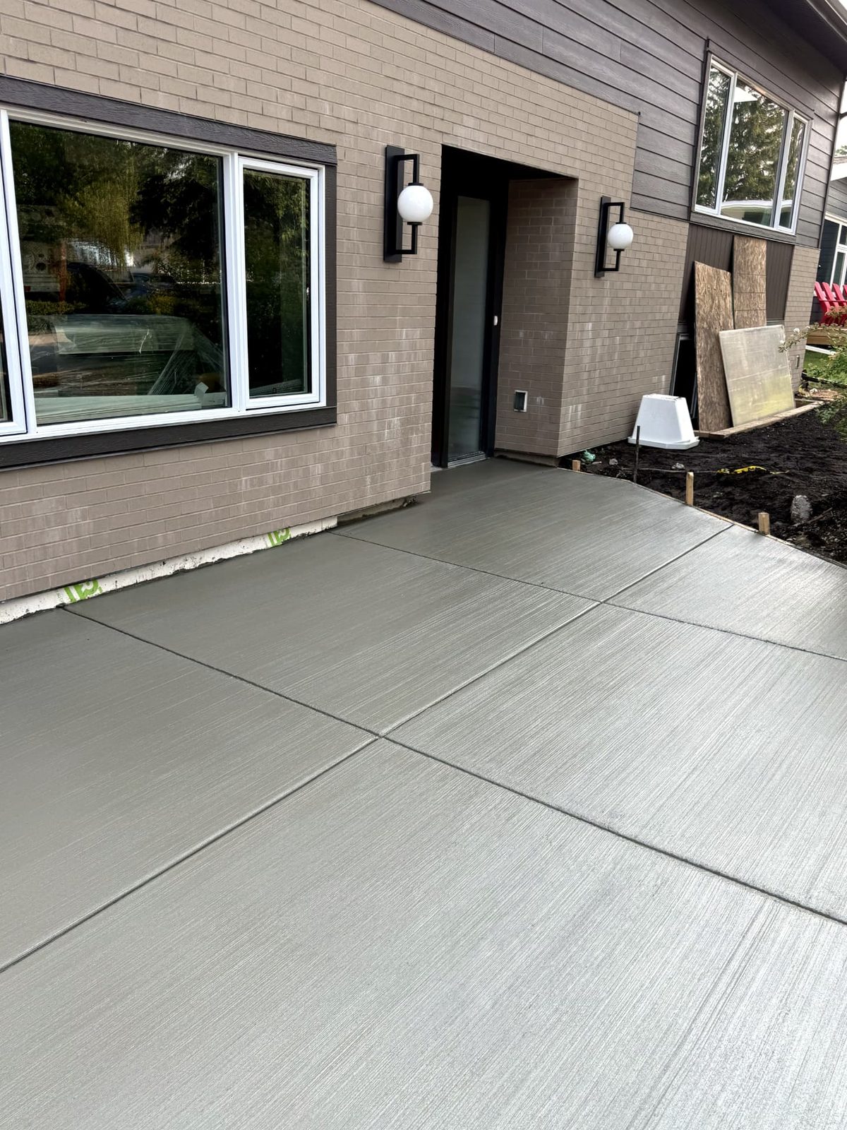 Broom-finished concrete patio and walkway with clean control joints alongside a Calgary home, poured by SiteWorx Concrete