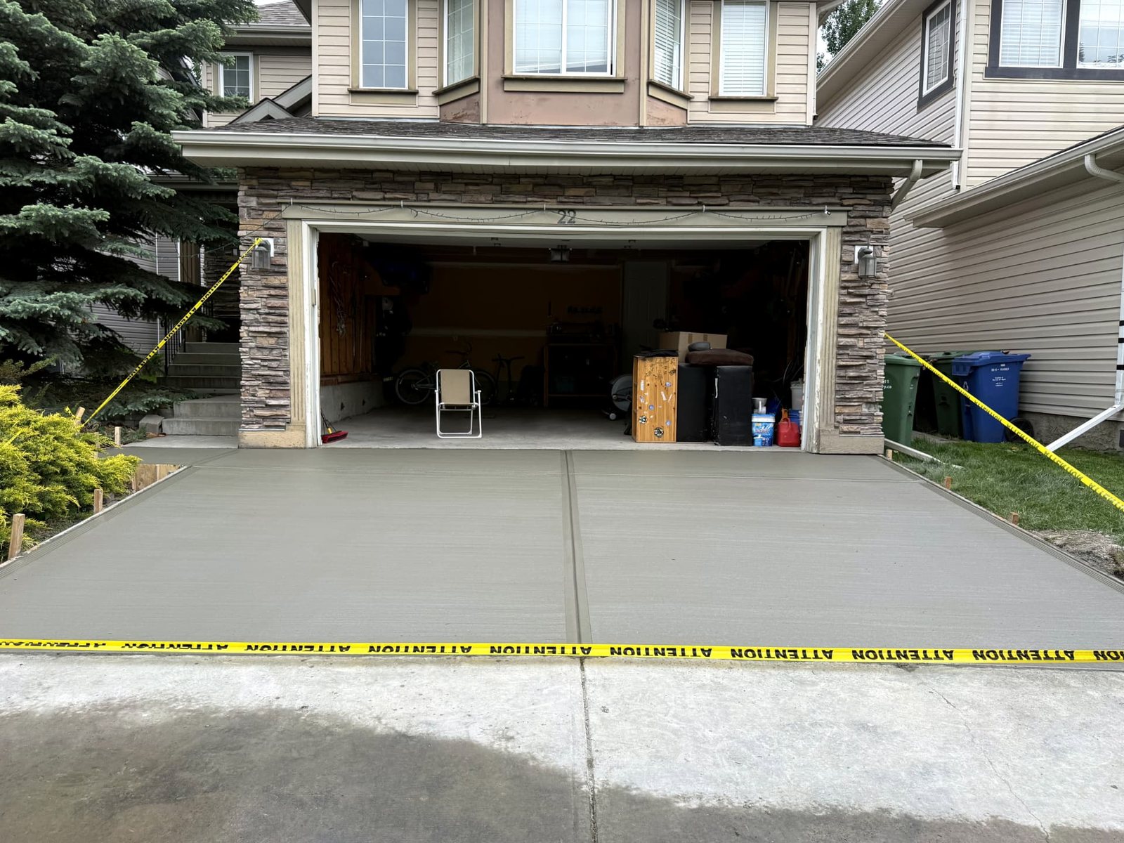 Freshly poured broom-finished residential concrete driveway in front of a double garage at a Calgary home, installed by SiteWorx Concrete