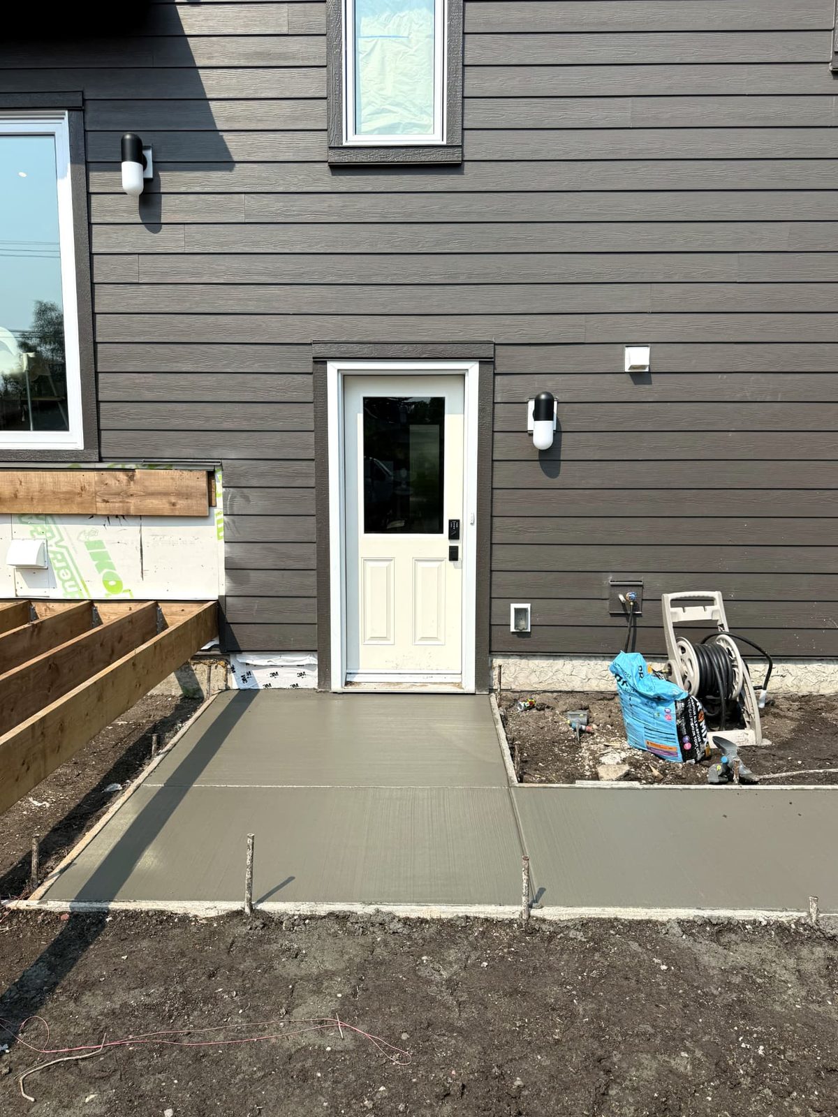 Freshly poured broom-finished concrete patio landing at a backyard entrance of a Calgary home, installed by SiteWorx Concrete