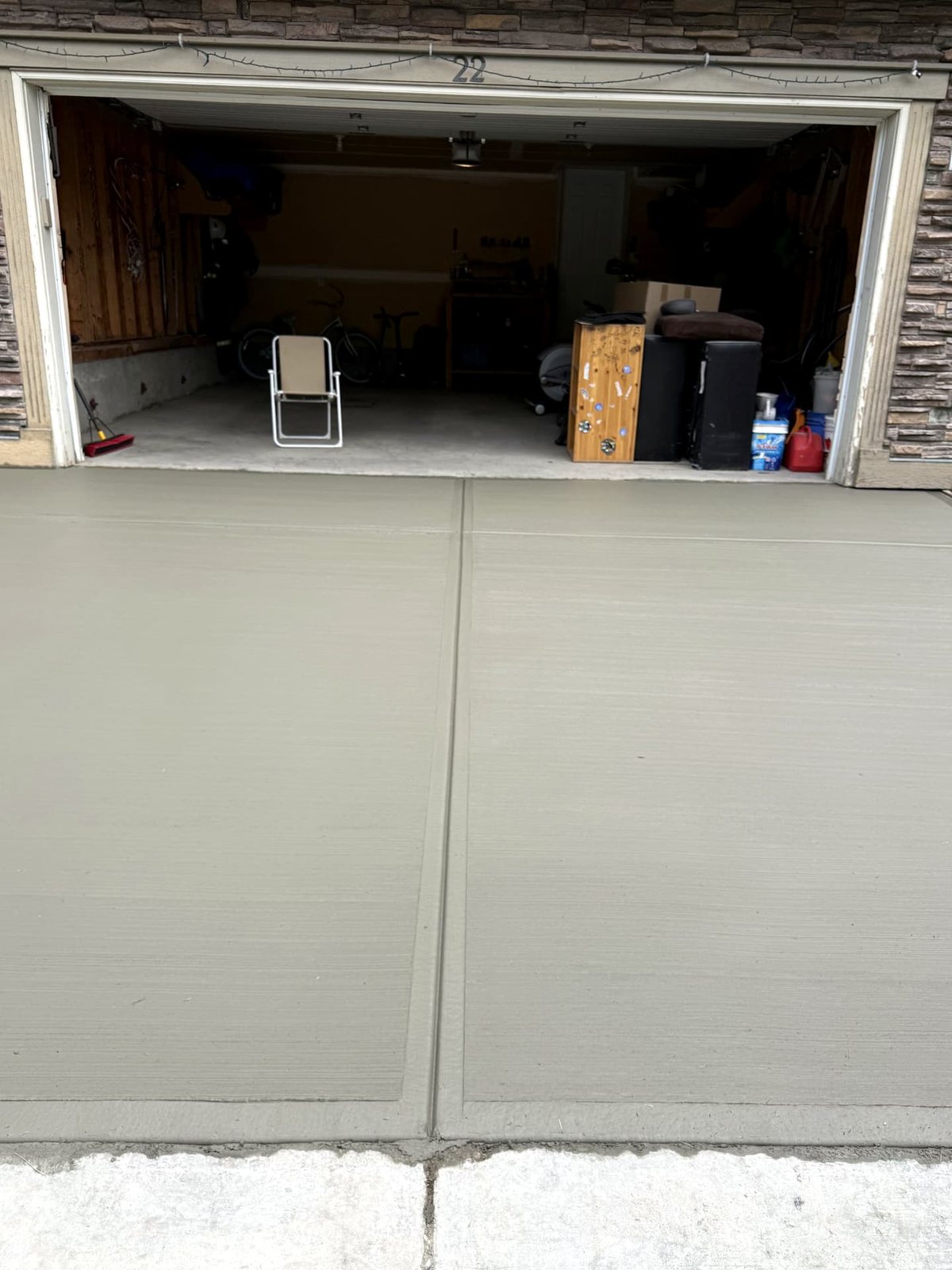 Close-up of a broom-finished concrete driveway and garage apron with tooled joints at a Calgary home, installed by SiteWorx Concrete