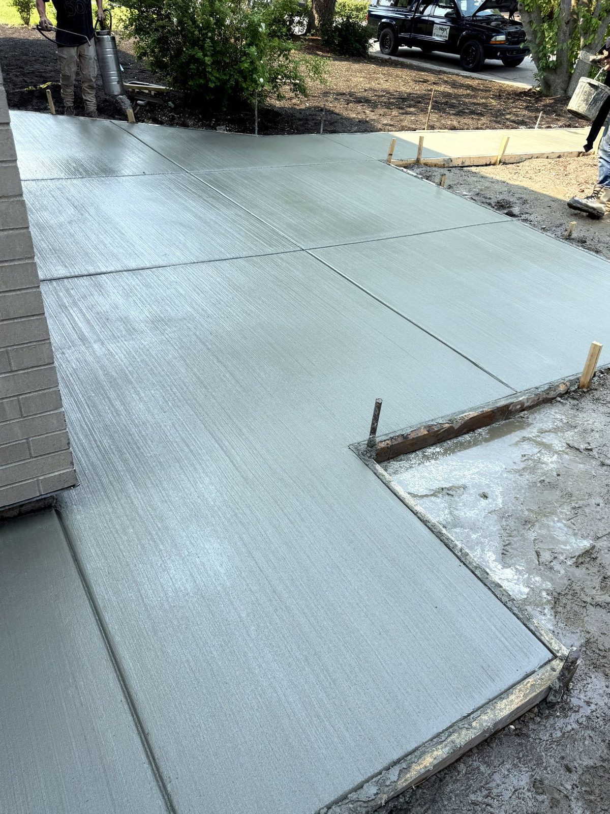 Large broom-finished concrete patio slab with clean saw-cut control joints and the SiteWorx Concrete crew finishing a Calgary backyard project