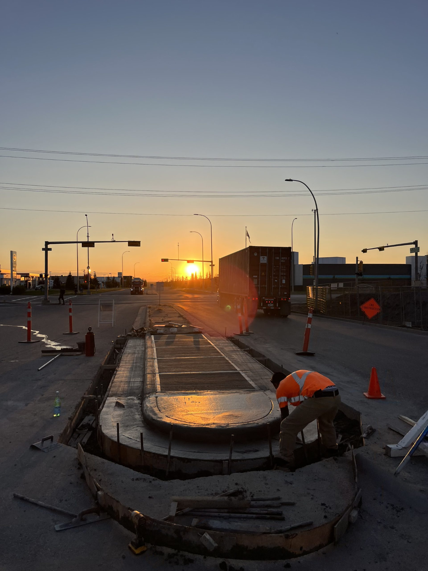SiteWorx Concrete crew finishing a curved commercial concrete curb and traffic island at sunset in Calgary, Alberta